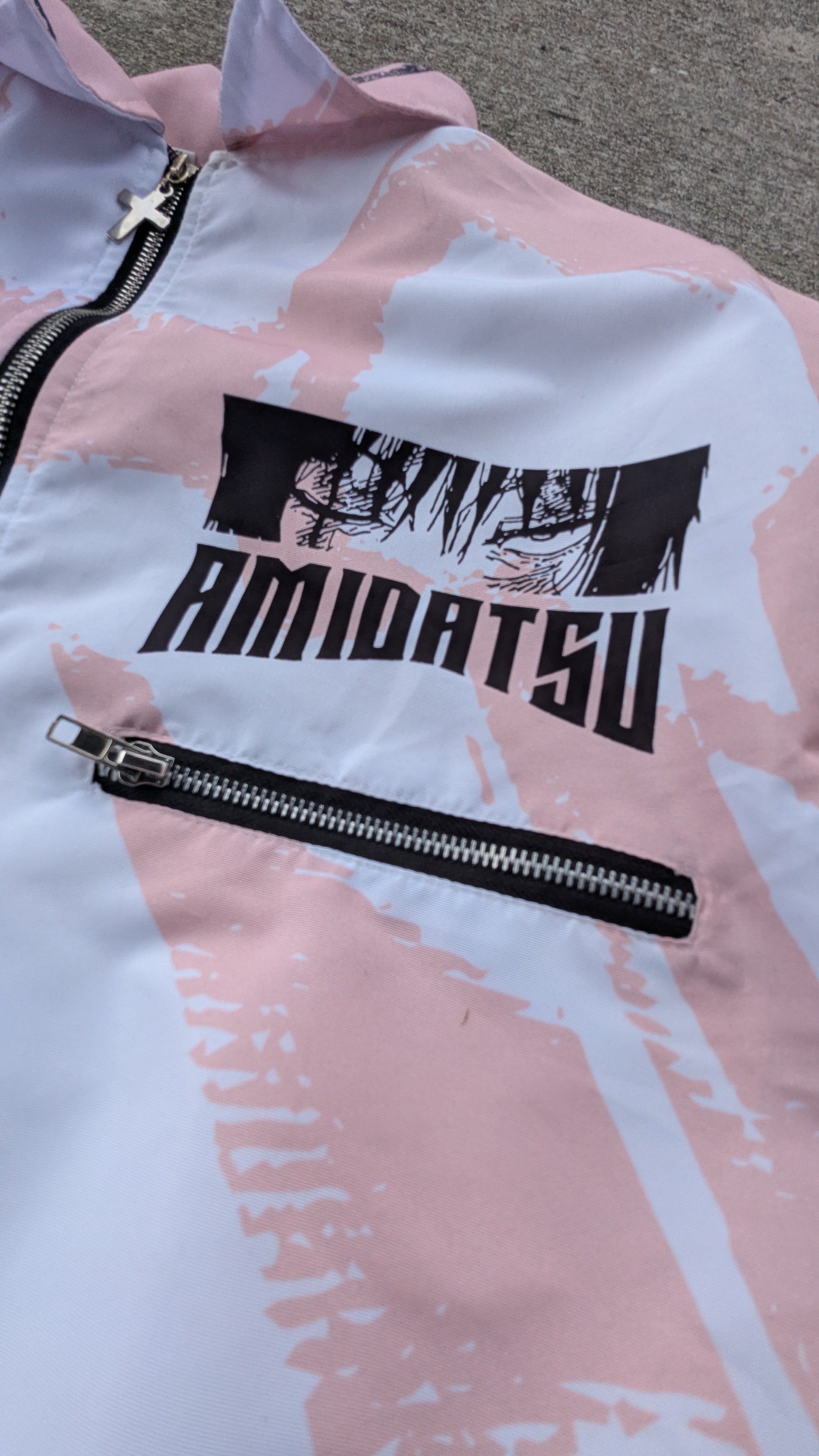 Pink and white jacket with black zipper and 'AMIDATSU' branding on a textured surface.