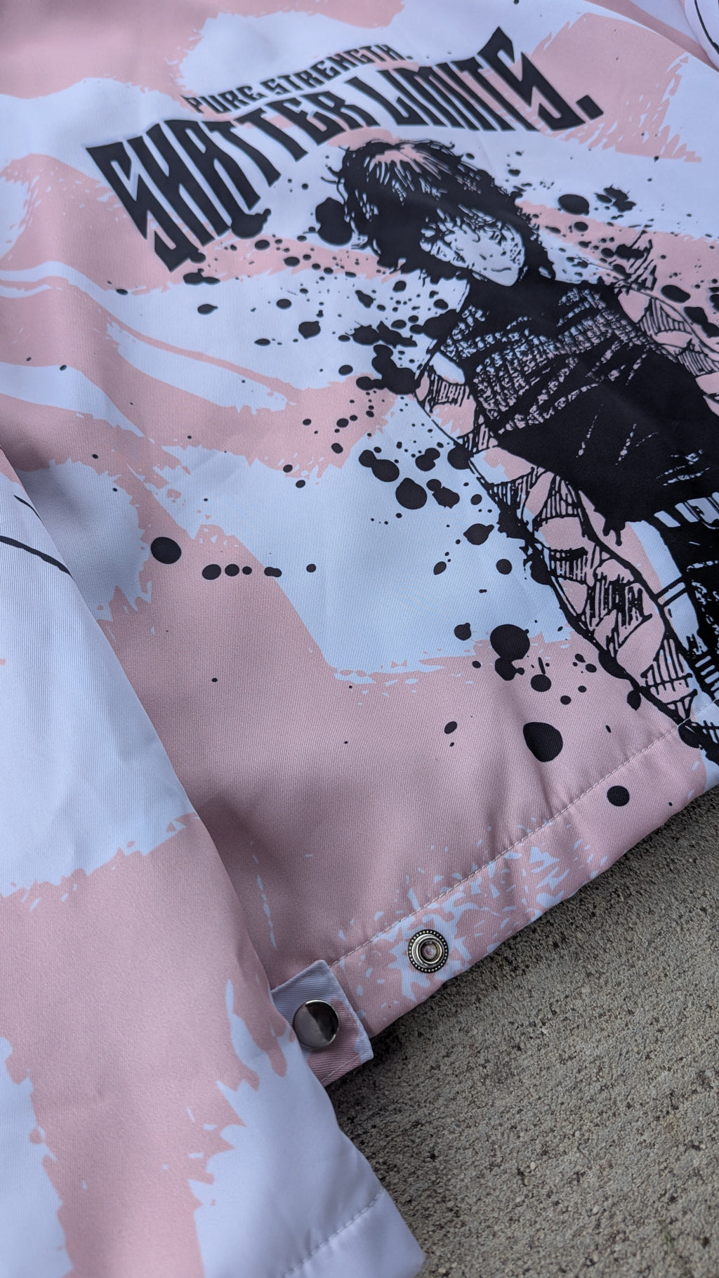 Pink jacket with black graphic design of a person and text on a textured surface