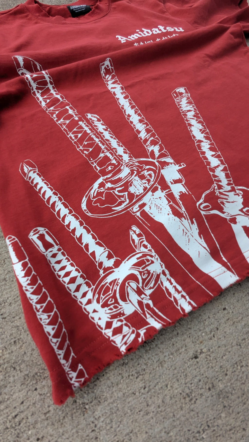 Red t-shirt with white graphic design on a concrete surface