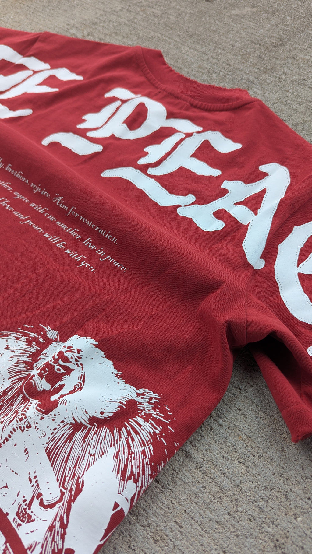 Red t-shirt with white text and graphic design on a textured surface